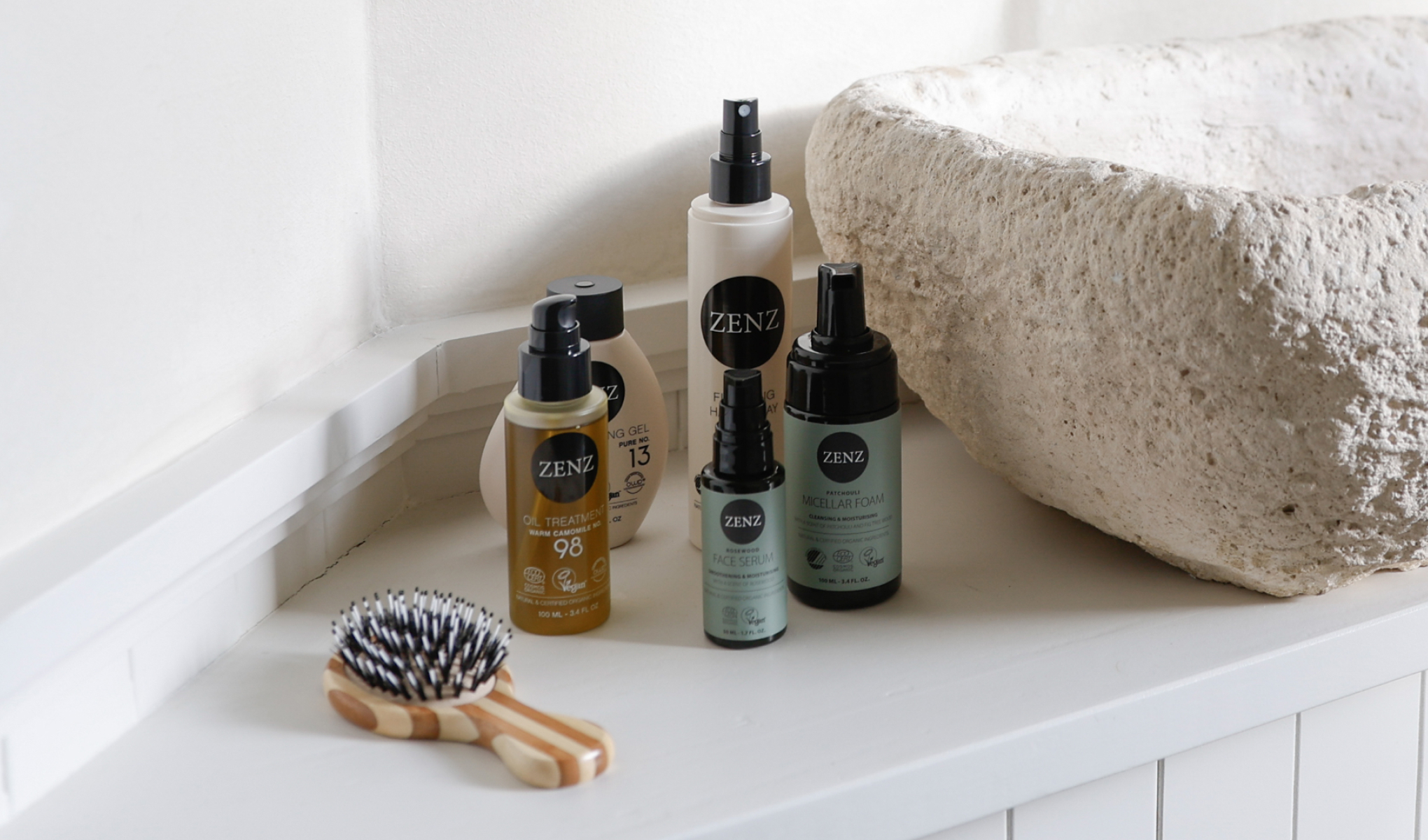 Zenz-produkter, inkludert olje-behandling, ansiktsserum, micellar-skum, stylinggel og hårspray. Bildet viser også en trehårbørste.