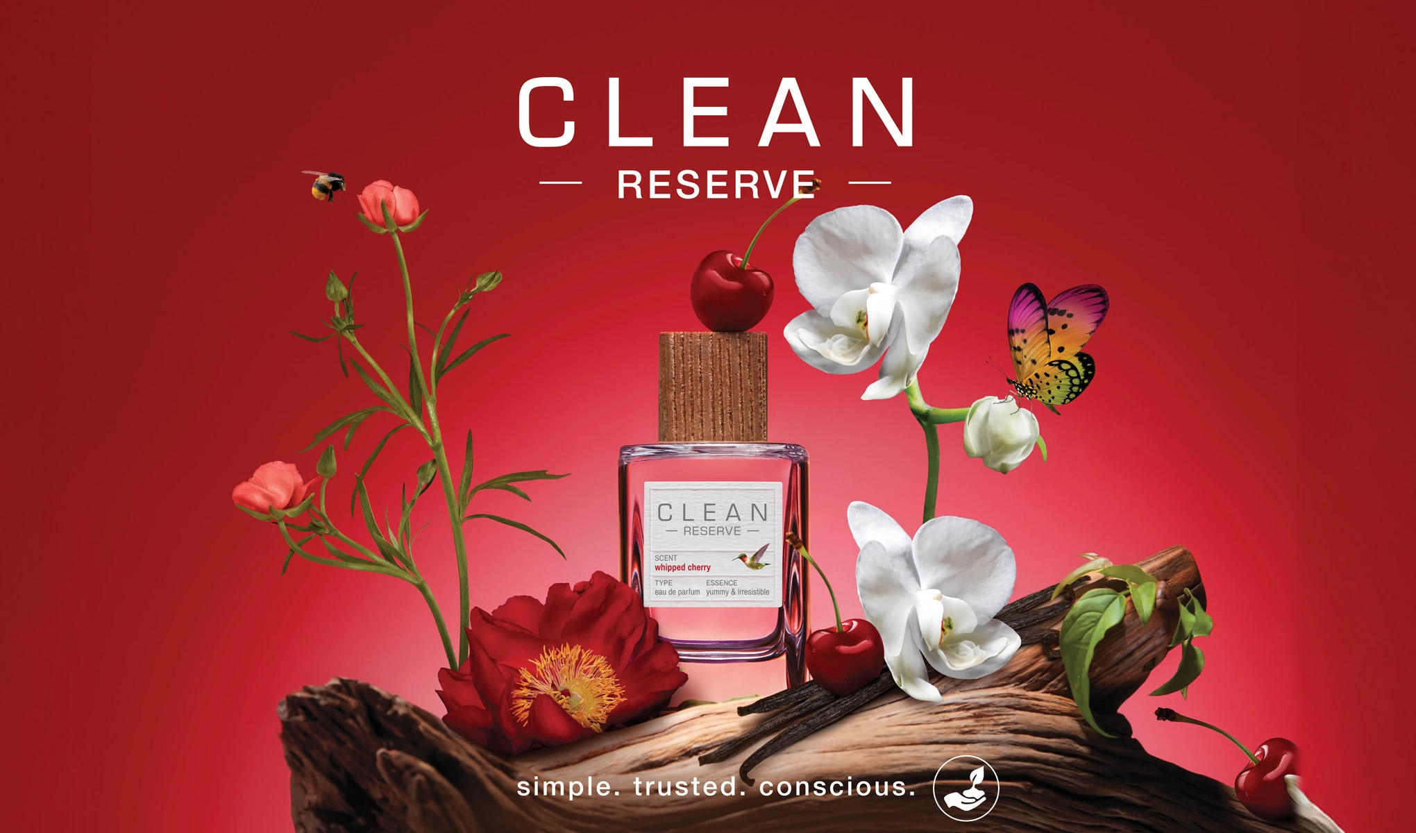 En flaska Clean Reserve-parfym, omgiven av blommor, körsbär och insekter på en röd bakgrund.