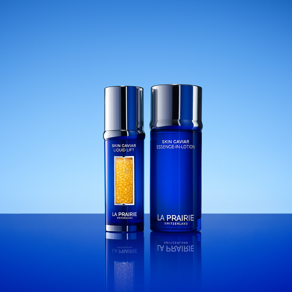 La Prairie Skin Caviar -hoitotuotteet sinisissä pulloissa, joissa hopeiset korkit, aseteltuna puhtaalle siniselle taustalle.