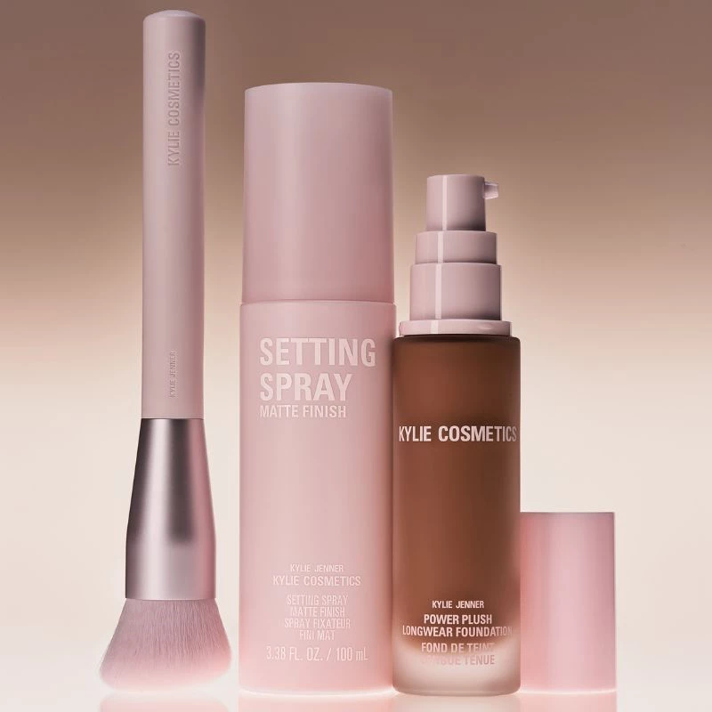Vaaleanpunaisia meikkipohjatuotteita Kylie Cosmeticsilta ruskeasta valkoiseen sävyyn vaihtuvalla taustalla.