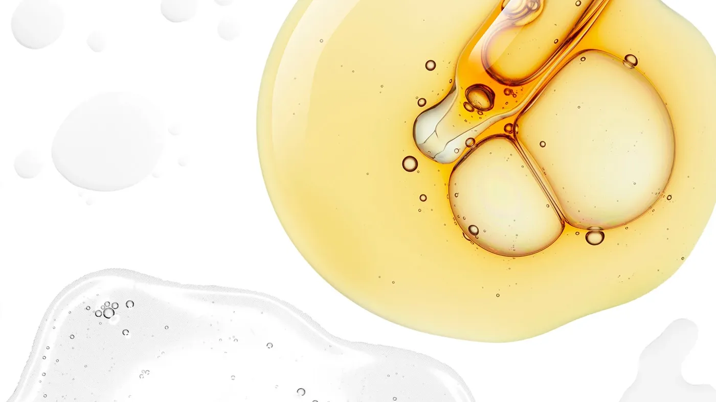 Dråper av serum i gult og hvitt mot en hvit bakgrunn.