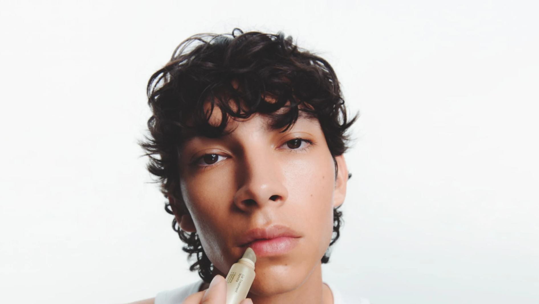 Närbild av en person som applicerar Lip Treatment Vanilla läppbalsam på sina läppar.