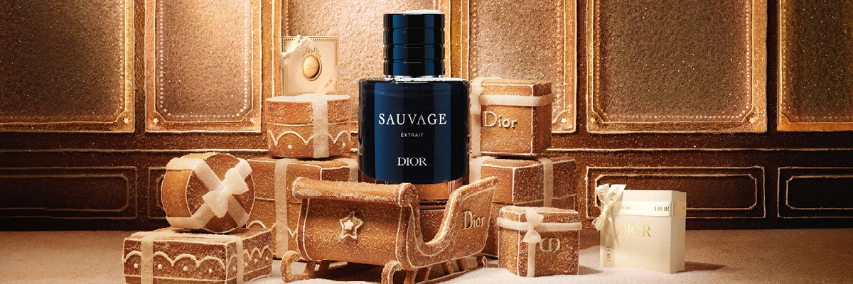 Dior Sauvage Extrait parfymeflaske på snødekket overflate, omgitt av pepperkakegaveesker og en slede, noen merket 'Dior'.