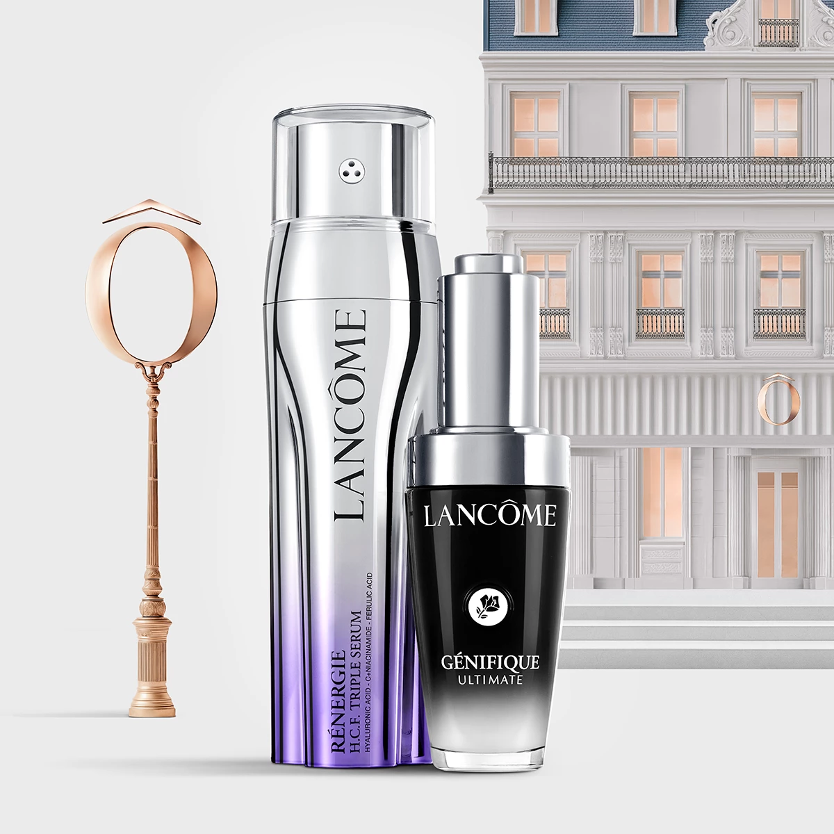 Kaksi Lancôme-ihonhoitotuotetta, Rénergie H.C.F. Triple Serum ja Génifique Ultimate, hopeanvärisissä pakkauksissa elegantin parvekkeella ja ikkunoilla varustetun rakennuksen edessä. Vasemmalla on lyhtypylväs.