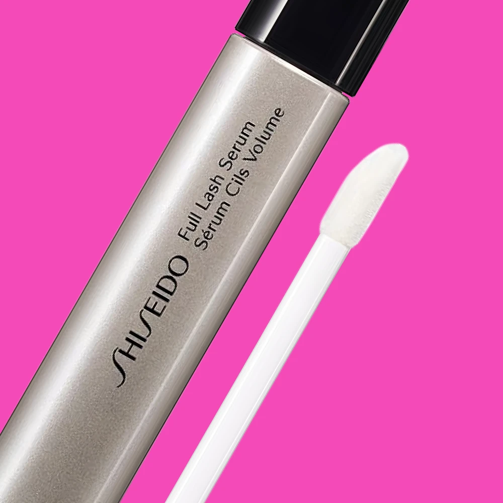 Shiseido Full Lash Serum, jossa on hopeanvärinen runko ja valkoinen applikaattori, vaaleanpunaisella taustalla.