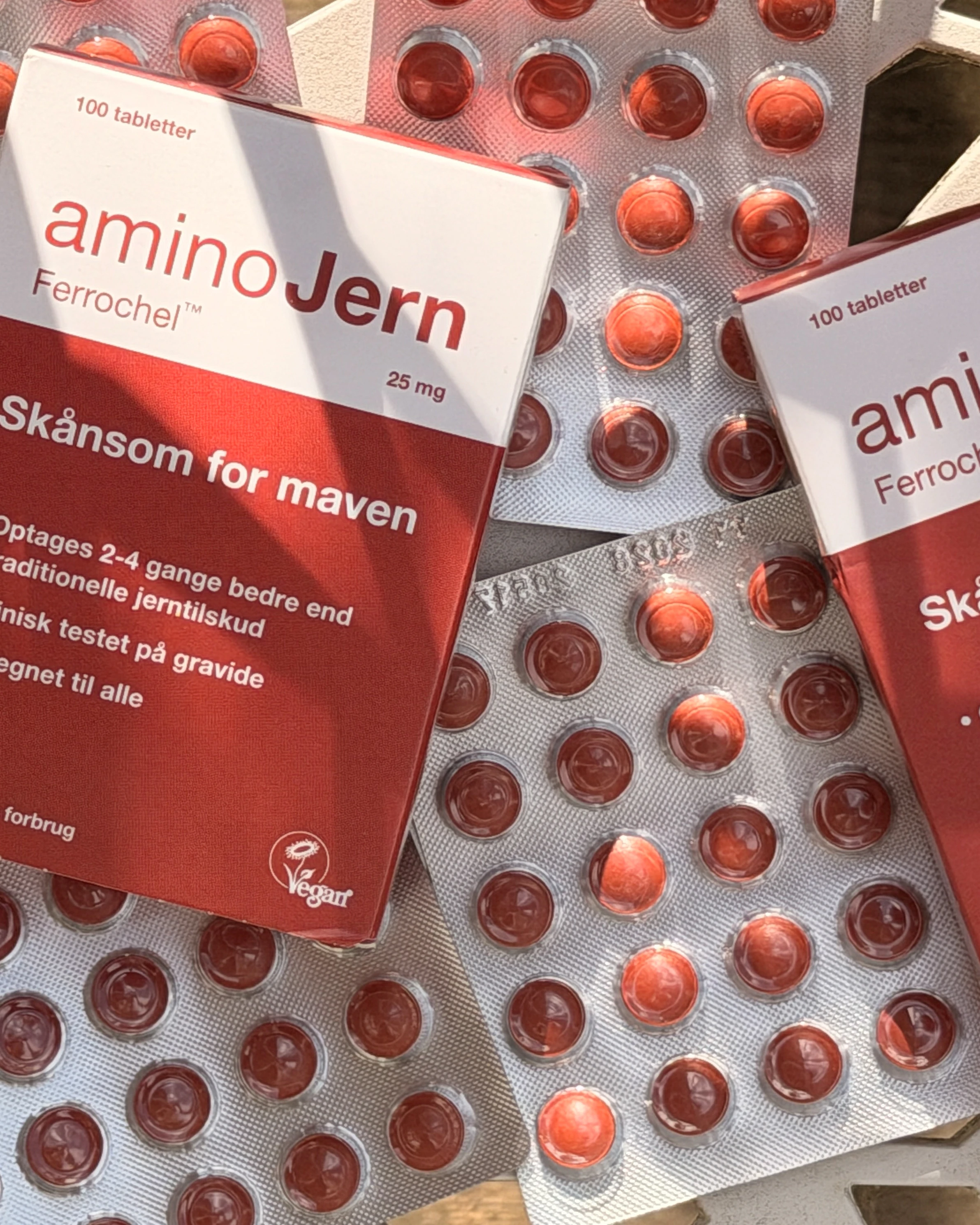 Pakke med aminoJern Ferrochel™ 25 mg jernpiller, 100 tabletter, skånsomme for maven, med blisterpakker af rødbrune piller.