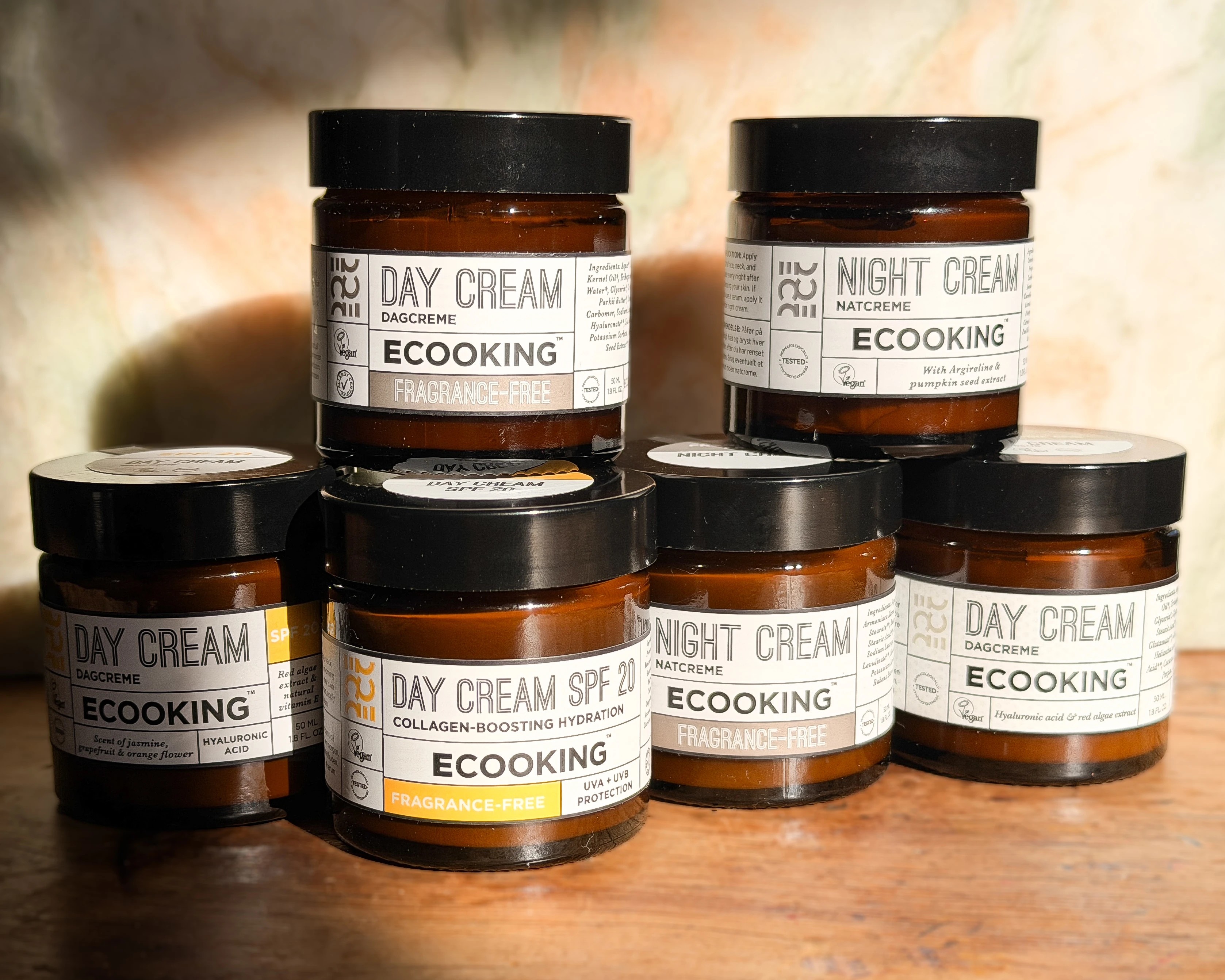 Et udvalg af Ecooking dag- og natcremer i brune krukker, herunder parfumefri, SPF 20 og anti-aging varianter.