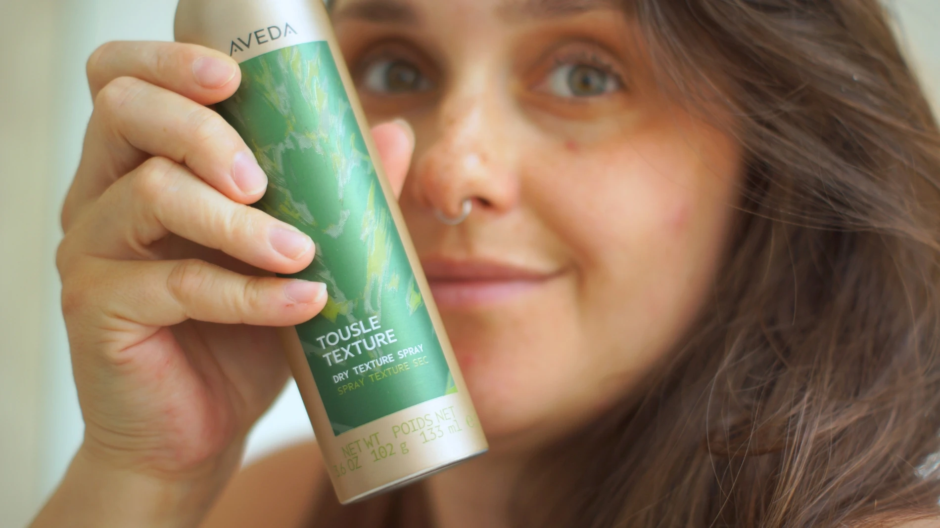 Billede af kvinde med voluminøst hår, der holder en texture spray