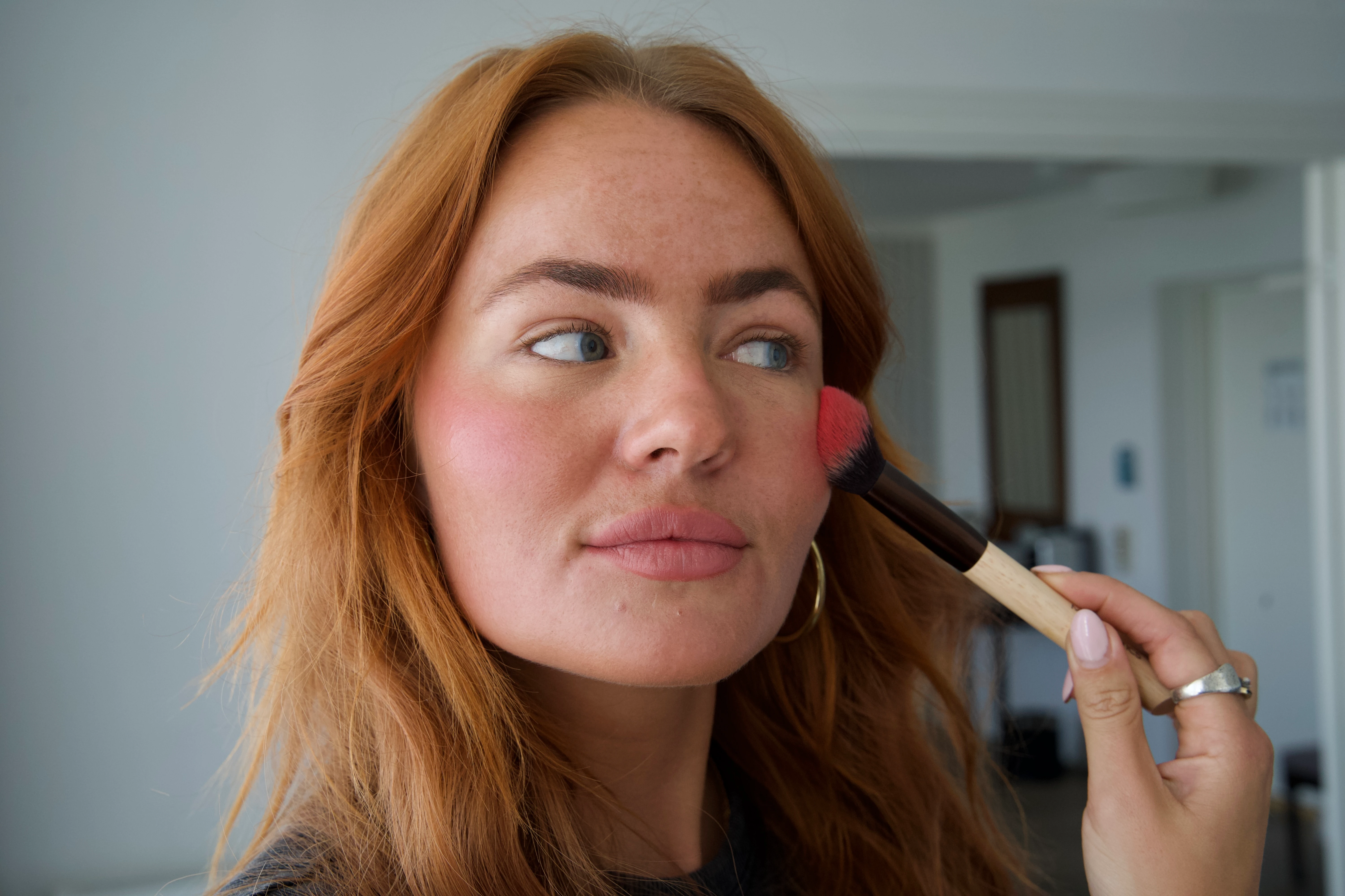 Ung kvinde, der bruger en makeupbørste til at lægge blush 