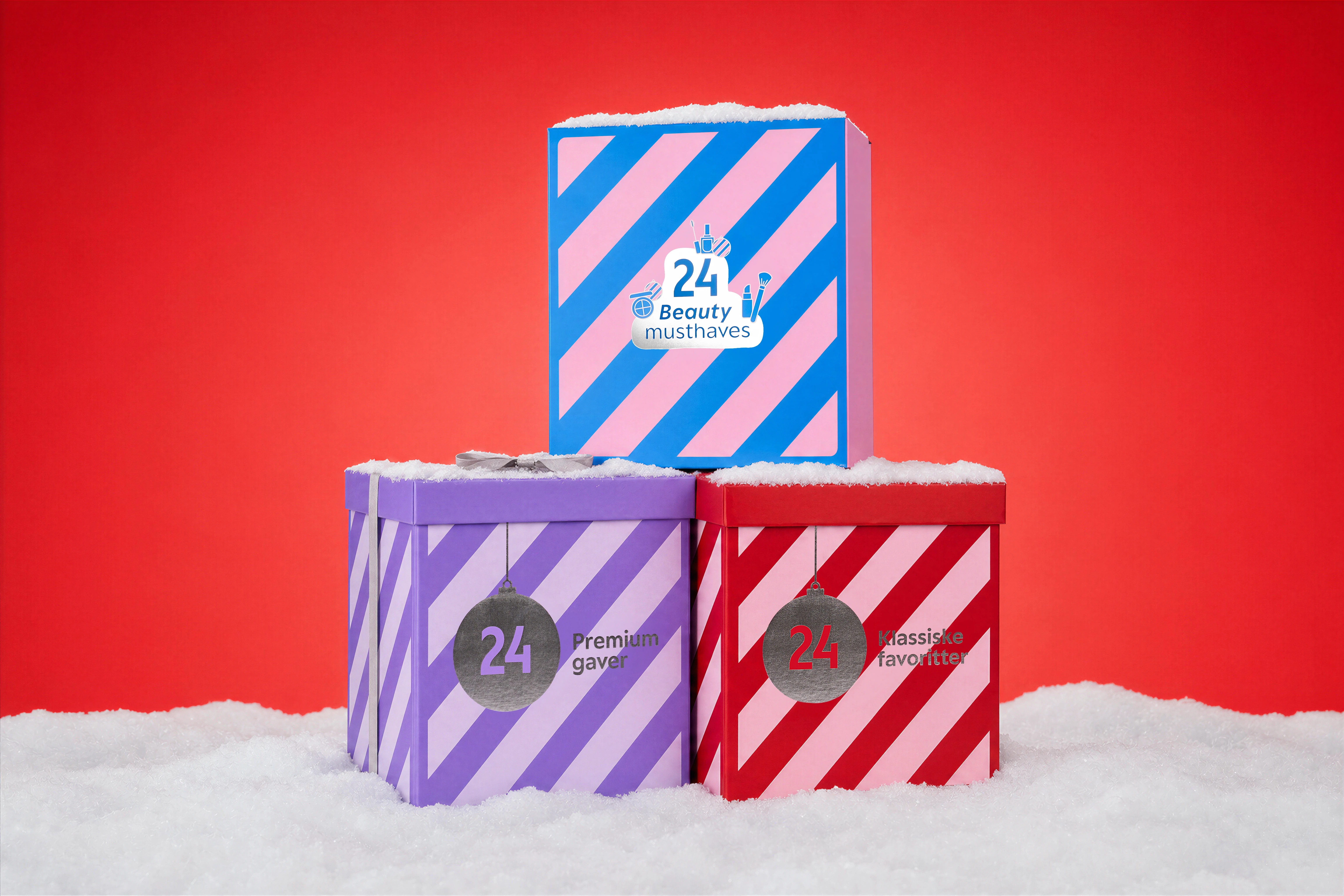 Tre stablede julekalendere i sne. Top: '24 Beauty musthaves'. Bund: '24 Premium gaver' og '24 Klassiske favoritter'.