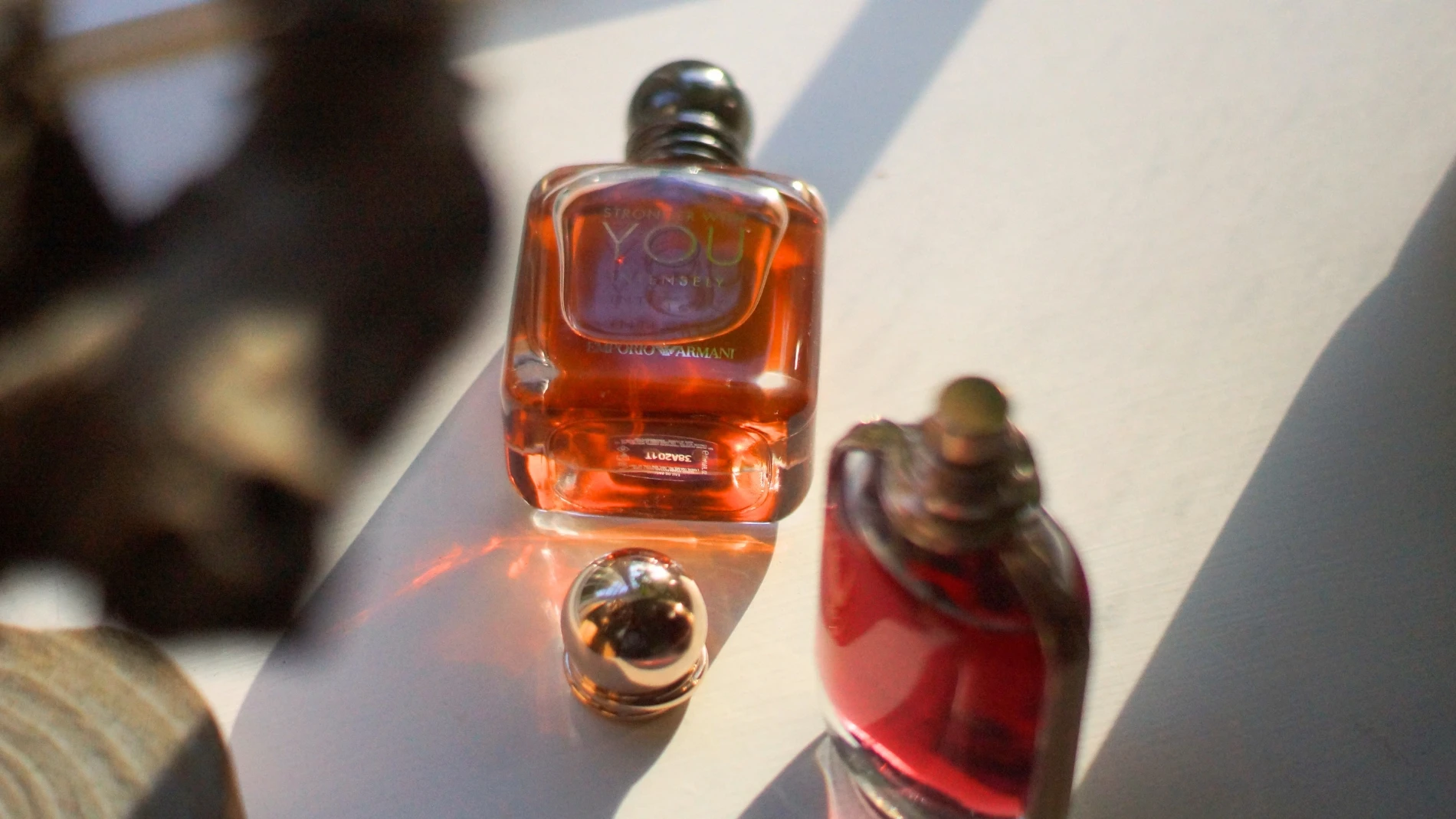 Emporio Armani Stronger With You Intensely parfumeflaske med ravfarvet væske, en mørk hætte og en separat guldhætte.