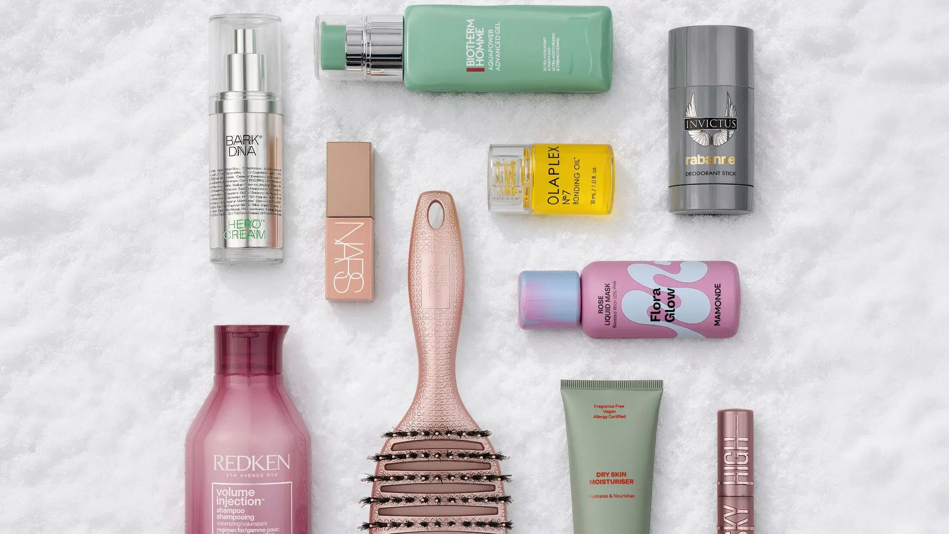 Udvalg af skønhedsprodukter, herunder Redken shampoo, Olaplex olie, NARS læbestift, en hårbørste og forskellige cremer og serummer.