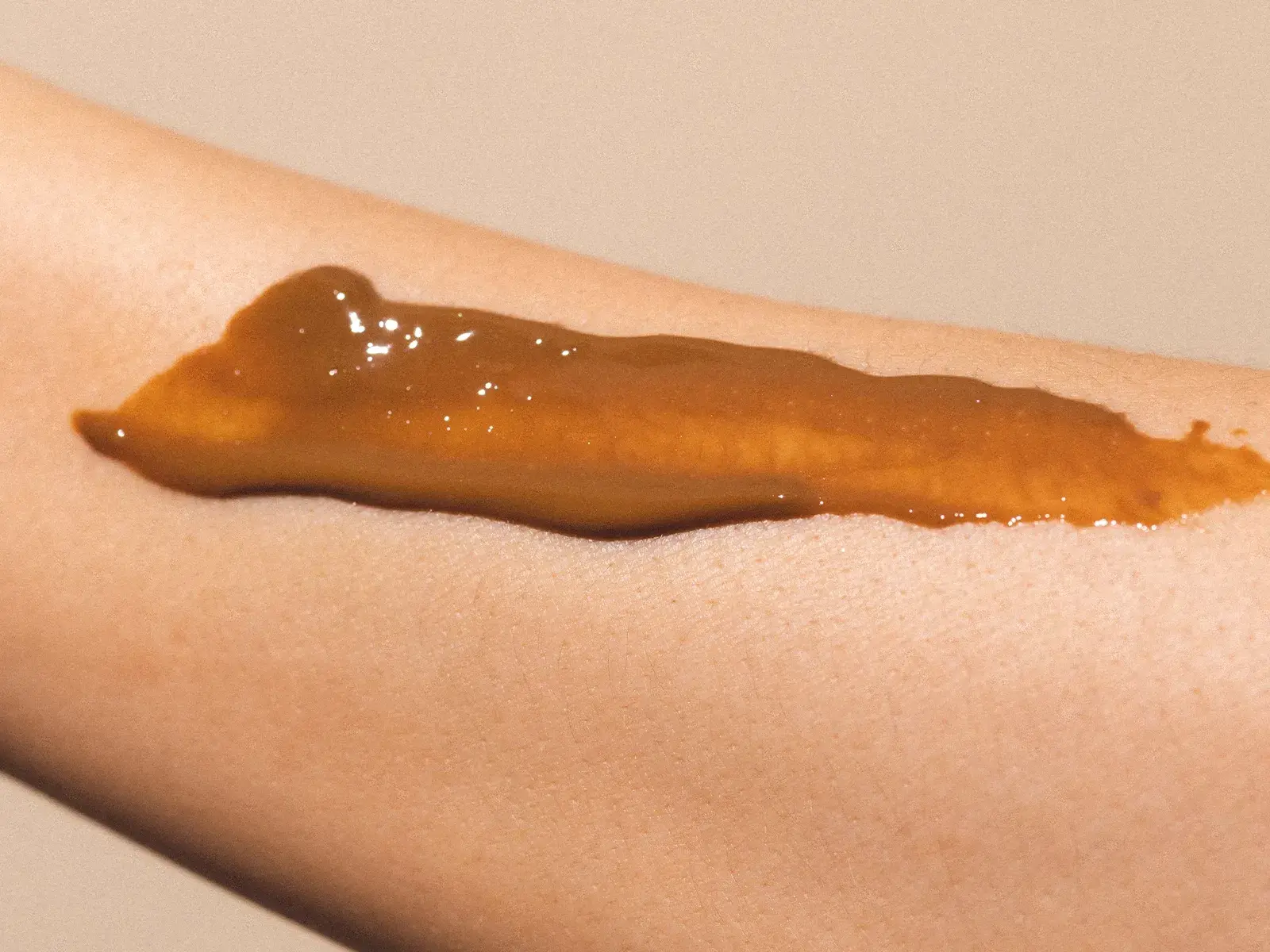En närbild av en arm med en brun creme applicerad på huden