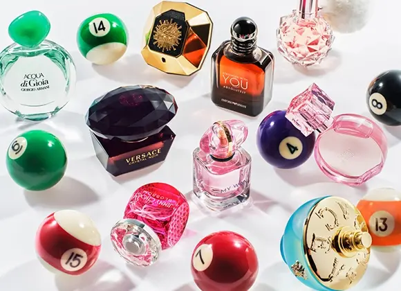 Kuva, joka näyttää useita hajuvesipulloja järjestettynä biljardipallojen joukkoon. Hajusteet sisältävät Acqua di Gioia Giorgio Armanilta, Versace Crystal Noir, Stronger With You Intensely Emporio Armanilta, My Way Giorgio Armanilta, ja muita. Tausta on valkoinen.
