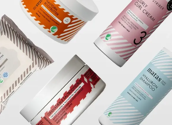 Erilaisten kauneustuotteiden kokoelma, joka sisältää bodybutterin, curl cream -voiteen, hyaluronisampoon, suolakuorinnan ja kasvopyyhkeitä. Tuotteet on tyylikkäästi aseteltu valkoista taustaa vasten