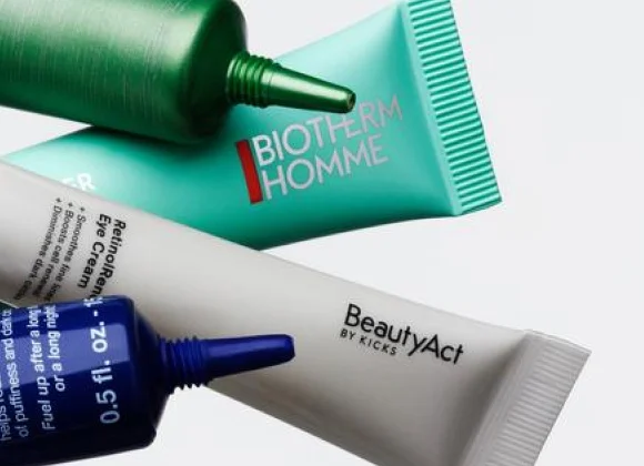 Fyra tuber med ögonkräm placerade diagonalt mot ljus bakgrund. En grön tub med texten ”Awakening Eye Cream” och ”Crème Réveil Contour des Yeux”, en turkos tub med texten ”BIOTHERM HOMME”, en grå tub med texten ”BeautyAct by KICKS” och ”RetinolRenew Eye Cream”, samt en blå tub med texten ”0.5 fl. oz”.