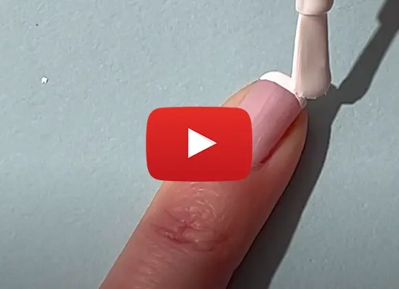 En närbild på en person som applicerar vitt nagellack på en ljusrosa nagel. Ett Youtube play-tecken är placerat i mitten av bilden.