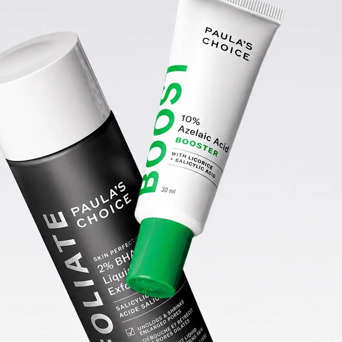 Två hudvårdsprodukter från Paula’s Choice visas mot ljus bakgrund: Skin Perfecting 2% BHA Liquid Exfoliant och 10% Azelaic Acid Booster med texten “PAULA’S CHOICE”, “BOOST” och “30 ml” synlig på förpackningarna. Produkterna marknadsför exfoliering och hudvård med salicylsyra och azelainsyra.