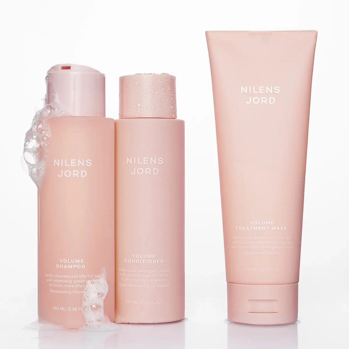 Tre rosa Nilens Jord hårprodukter: Volume Schampo med skum, Volume Balsam och Volume Hårinpackning.