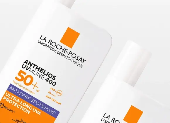 Två vita flaskor med solskyddet La Roche-Posay Anthelios UVMune 400 SPF 50+ syns mot ljus bakgrund. Förpackningen visar texten ”Very high protection 50+”, ”Anti-dark spots fluid” och ”Ultra-long UVA protection”.