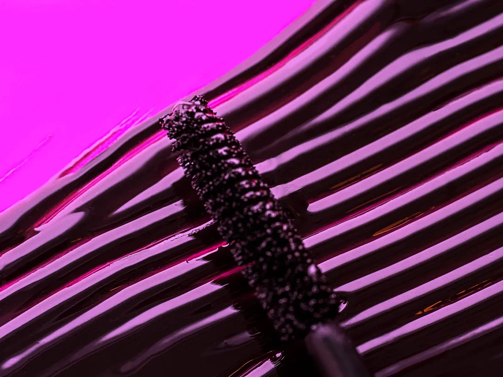 Mascara genomstruken med en mascaraborste i lila ljus 
