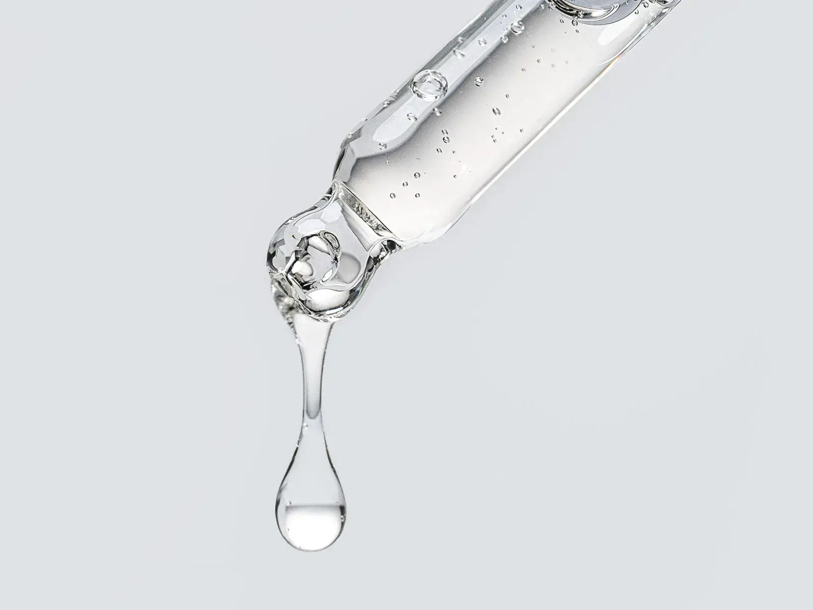 En närbild av en pipett som släpper en droppe klar vätska.