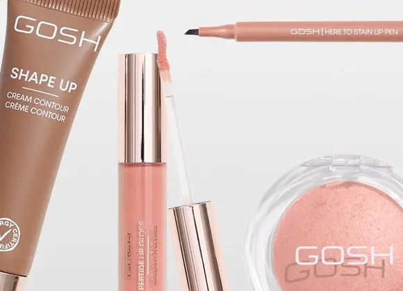 Närbild på sminkprodukter från GOSH: Shape Up Cream Contour Crème Contour med Allergy Certified-symbol, Here To Stain Lip Pen, Peptide Lip Gloss Brilliant Lip Glaze med applikator samt ett runt puderrouge med GOSH-logotyp. Produkterna visas i nude- och rosatoner mot ljus bakgrund.