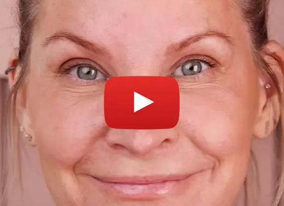Närbild på person som tittar leende in i kameran med en YouTube-spelknapp över.