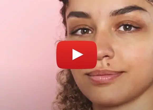 Mørkhåret jente mot rosa bakgrunn. You-Tube-knapp i midten.