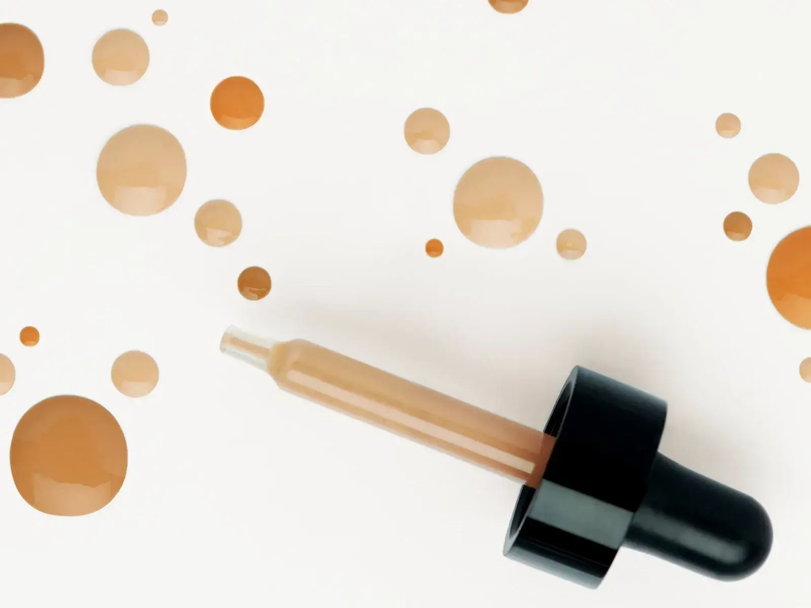 En pipett med bb cream och flera droppar av produkten på en vit bakgrund.