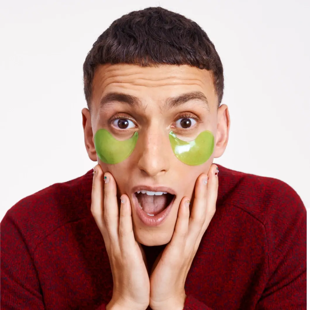 Person med grønne øyemasker ser overrasket ut med hendene på kinnene.