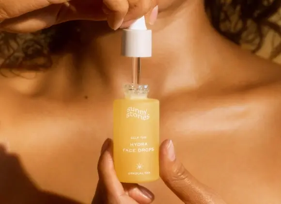 Henkilö pitää kädessään Sunny Stories Hydra Face Drops -pulloa.