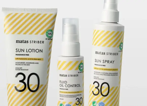 Tre solbeskyttelsesprodukter fra Matas Striber: en tube “SUN LOTION”, en pumpeflaske “FLUID OIL CONTROL” og en sprayflaske “SUN SPRAY”, alle med gule diagonale striper og teksten “FRAGRANCE FREE”. Emballasjen viser “with hyaluronic acid & aloe vera”, “with glycerin and antioxidant vitamin E”, “HIGH SPF 30”, “WATER RESISTANT” samt merkinger som “RECYCLED 62% PLASTIC” og “RECYCLED 50% PLASTIC”.