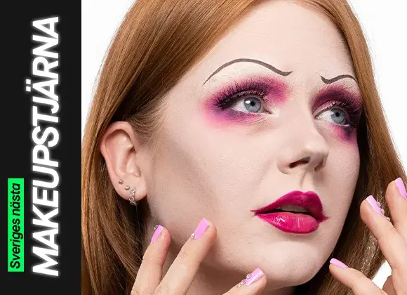 En person med en kreativ makeuplook i rosa toner, med markerad ögonmakeup, långa fransar, skarpt målade tunna ögonbryn och glansiga ceriserosa läppar, där händerna med rosa naglar ramas in omkring ansiktet.