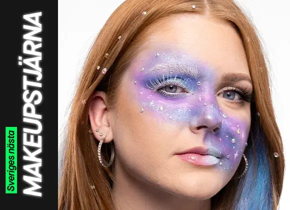 Närbild på galaxinspirerad makeup i lila, blå och silver med vita fransar, glittrande stenar och målade stjärnformationer, medan en ögonlockssida är öppnad och den andra stängd för att visa effekten.