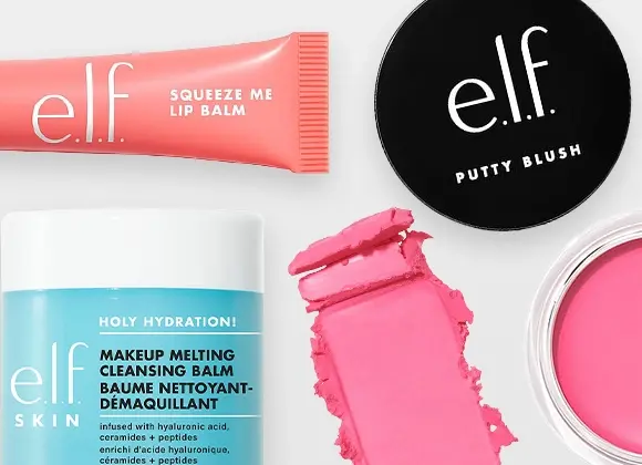 Produktbilde med flere e.l.f.-produkter på lys bakgrunn: en tube med leppebalm, en krukke med rensende balm med blå etikett, en åpen krukke med rosa kremprodukt, et rundt svart lokk med e.l.f.-logo og et utstrøket rosa kremprodukt i midten.
