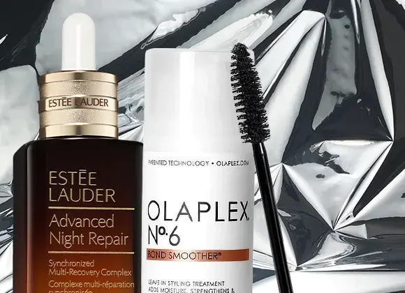 Lähikuva kolmesta kauneustuotteesta hopeisella taustalla: Estée Lauder Advanced Night Repair -seerumi, Olaplex No.6 Bond Smoother ja musta ripsiväriharja.