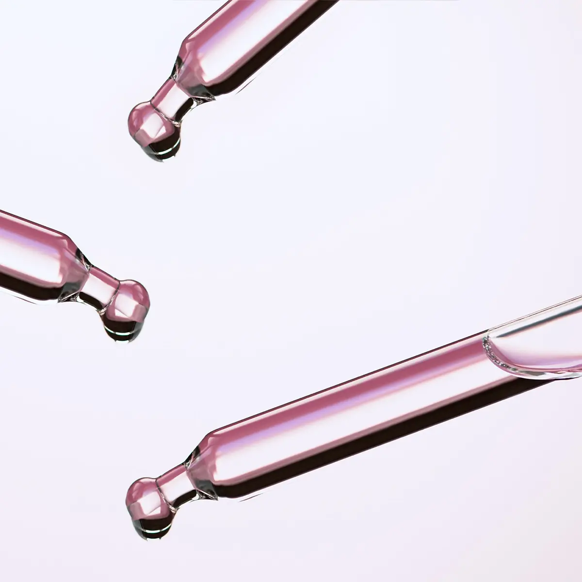 Tre glaspipetter med rosa serum syns mot en ljus bakgrund, med droppar i pipetternas spetsar. Bilden lyfter fram ett hudvårdsserum och dess flytande konsistens i en ren, minimalistisk produktmiljö.