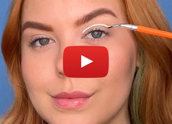 Kvinna som aplicerar eyeliner mot en blå bakgrund