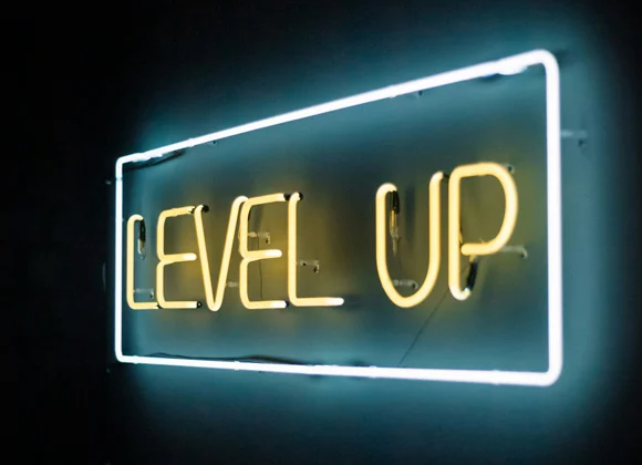 Neonskyld med texten "LEVEL UP" i gult och med en blå ram runt