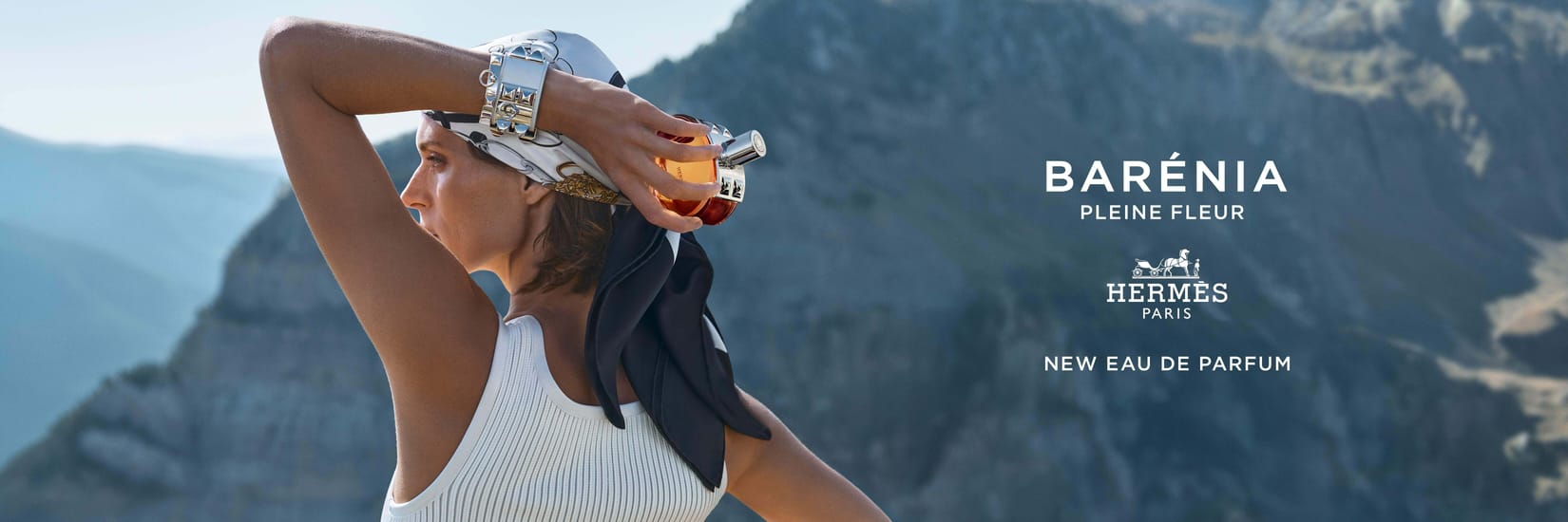 Hermès Barénia Pleine Fleur Eau de Parfum med model foran et bjerglandskab og Hermès-logo samt produktnavn.