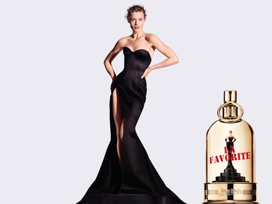 Her ses et kampagnebillede for Jean Paul Gaultier La Favorite. En person i en lang sort kjole står ved siden af parfumeflakonen. På billedet står “Jean Paul Gaultier”, “La Favorite” og “Gaultiers nye feminine duft”