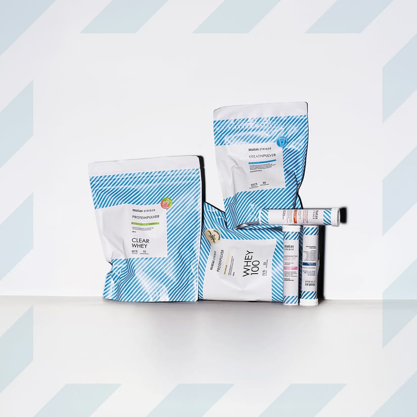 Her ses et udvalg af Matas SportStriber med blandt andet Clear Whey proteinpulver, Whey 100, kreatinpulver og elektrolytter. Produkterne har hvide emballager med blå striber og er arrangeret samlet mod en lys baggrund med lyseblå stribedetaljer.